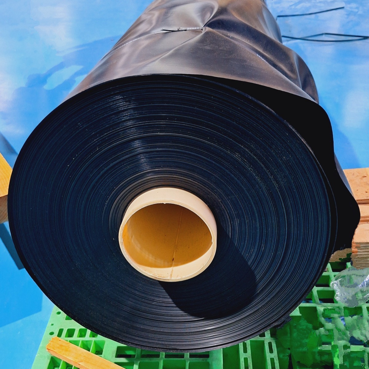 A roll of black LDPE film on a green pallet, photographed by CJ Polymers