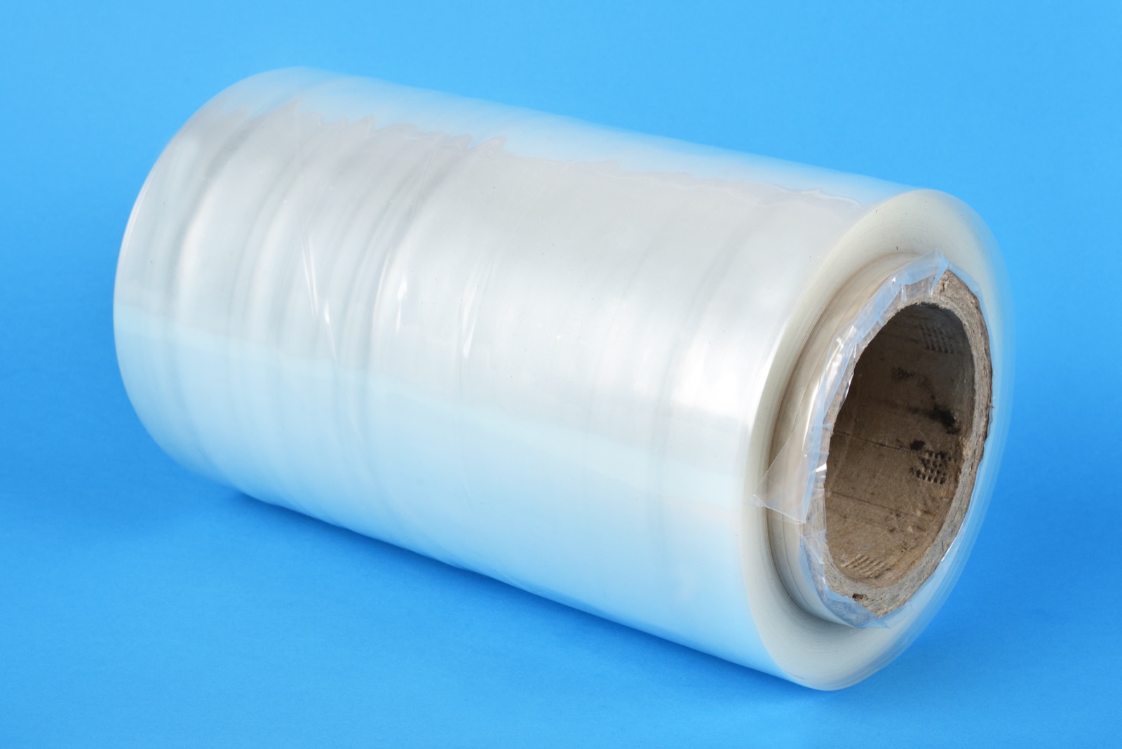A roll of clear polyethylene film on a blue backdrop, from CJ Polymers' product photography