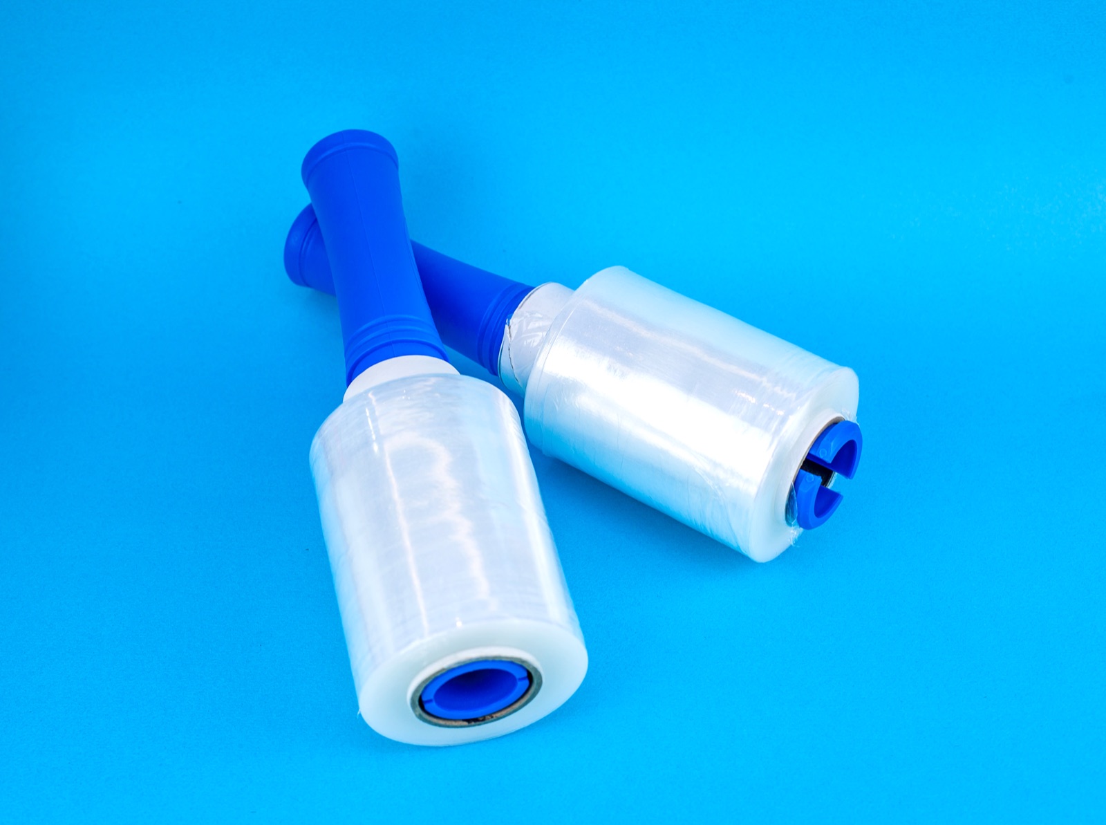 Two stretch-film hand rolls with blue dispensers on a blue backdrop, from CJ Polymers' product photography
